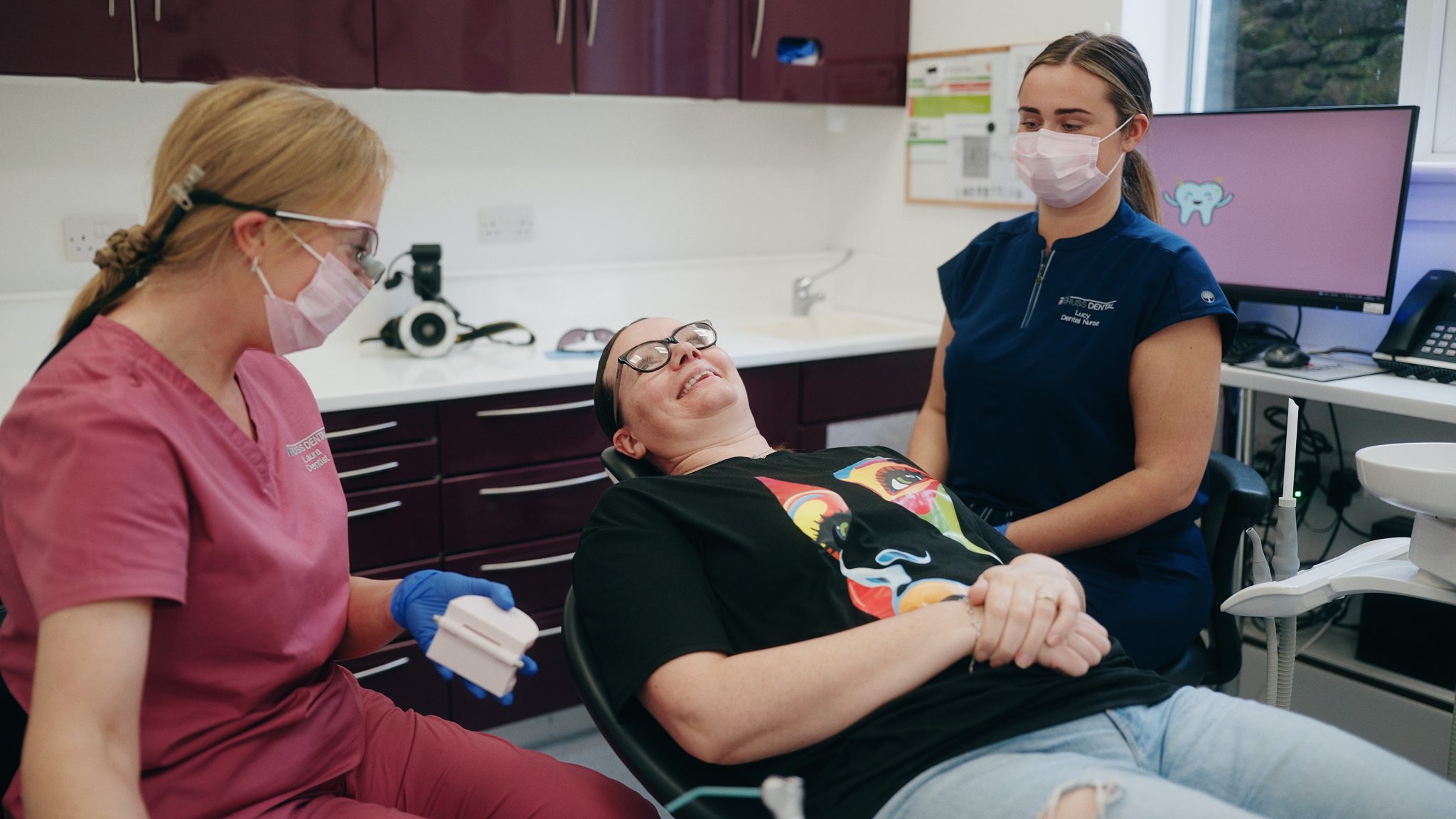 Still from a dental treatment explanatory video a dentist and a dental nurse next to a patient